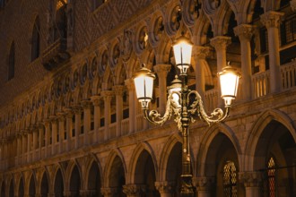 Illuminated street lamp in front of a magnificent Venetian façade at night, Doge's Palace, St