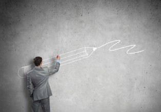 Rear view of businessman drawing sketches on wall