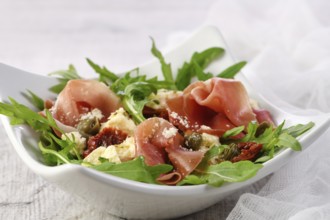 Arugula salad, prosciutto with sun-dried tomatoes, slices of mozzarella, capers, seasoned with