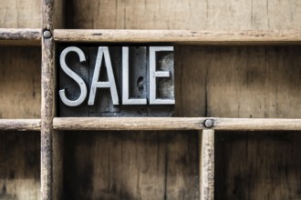 The word SALE written in vintage metal letterpress type sitting in a wooden drawer