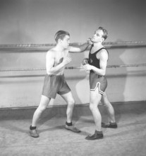 Boxing in the old days. Two young boxers facing each other, dressed for boxing but lacking boxing