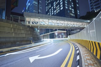 Empty asphalt city street road with walkway bridge and light trail, night scene