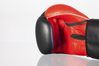 Red and black boxing gloves on a glass table isolated on white background