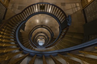 Elegant spiral staircase with wooden railing in a building, abstract view from above,