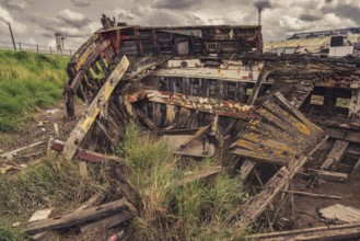 A derelict shipwreck with dark clouds over it, seen in King's Lynn, Norfolk, England, UK