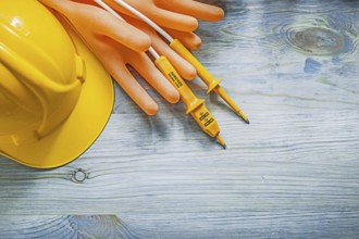 Safety building helmet electrical tester orange dielectric gloves on wood board electricity concept