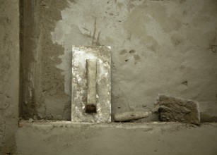 Dirty grunge cement trowel hand tools on fresh mortar wall