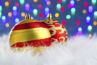 Christmas baubles on white fur and colorful lights