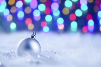 Christmas silver bauble in colorful blurred lights background