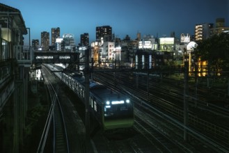 Train passes the Uguisudani railway station in Tokyo at night. Numerous hotels can be seen in the