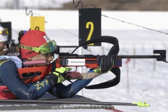 Sportswoman biathlete aiming, rifle shooting, reloading prone position. Biathlete Polina Yegorova