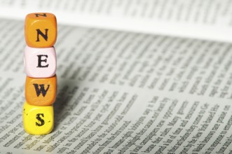Word news.Wooden cubes on newspaper. Close up studio shot