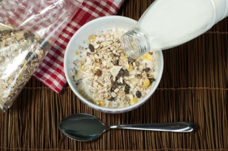 Muesli breakfast in package.Bottle milk and spoon. Pouring milk in a bowl