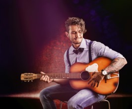 Handsome young man in bow-tie with guitar looking at camera.Studio shot