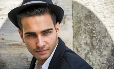 Headshot of handsome young man outdoor in the sun with fedora hat