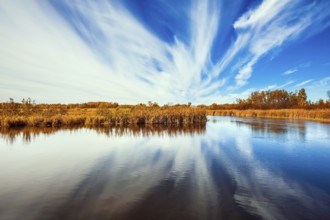 Cirrus clouds are reflected in the Winnipeg River. Wonderful autumn day in Manitoba. Old Pinawa Dam