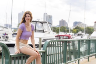 A gorgeous redhead model enjoys the perfect summer weather at a local marina, surrounded by boats