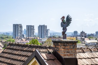 Weathercock on chimney above old town roofs