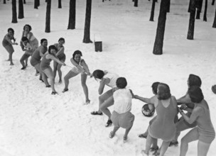 Tug of war wintertime. Two teams of women in bathingsuits are having a tug of war in the snow.