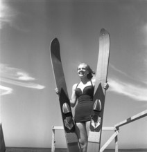 1950s on the beach. A young woman on the seaside is going to try the relatively new water sport,