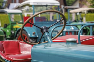 Detail of a tractor with red seat and steering wheel in the foreground, südlohn, münsterland,