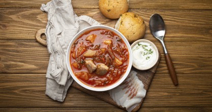 Ukrainian Borscht, red beetroot soup with meat, in white bowl with sour cream, garlic buns