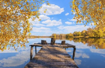 Wooden fishing pier on calm river in autumn