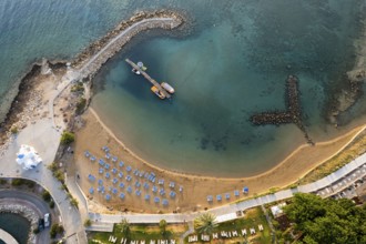 Drone aerial of tropical sandy beach. Beach umbrellas people swimming and relaxing. Summer