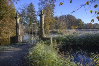 An open iron gate in a frosty garden, surrounded by autumnal colours and sunlight, borken, North
