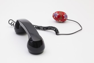 Old phone reciever and cord connection with Easter eggs. Easter hotline concept