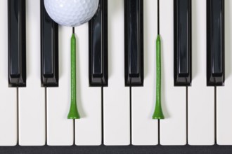 Virtuosic game - Piano keyboard and different golf balls and wooden tees