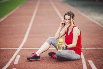 Sport and technology. A beautiful young Caucasian woman with ponytail sitting resting after workout