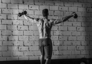 Gym man rising hex dumbbells weightlifting rear view