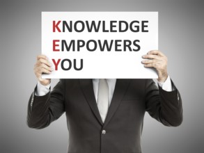 A business man holding a paper in front of his face with the text Knowledge Empowers You