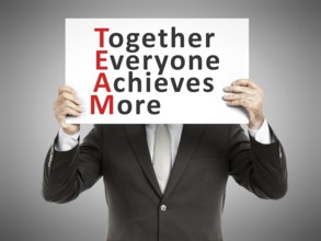 A business man holding a paper in front of his face with the text Together Everyone Achieves More
