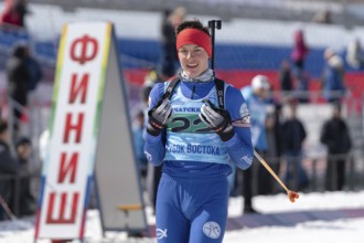 Portrait of sportsman biathlete Sporshev Nikita at finish line after skiing and rifle shooting.