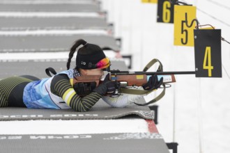 Sportswoman biathlete Lee Hyunju South Korea rifle shooting in prone position. Biathlete in