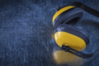 Noise reduction protective earmuffs on scratched metallic surface construction concept