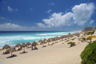 Umbrellas on a sandy beach with azure blue water on a sunny day near Cancun, Mexico, Central