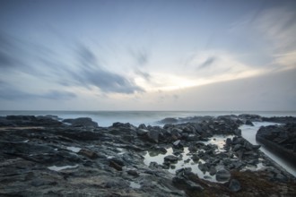 Beach, with lava rocks and vegetation, view of the sea in the evening at sunset. Landscape with