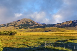 The huge possessions of a private hacienda are surrounded by distant mountains. The grass field is