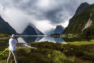 New Zealand. The famous ocean fjord Milford Sound. The gray-haired tourist photographs a
