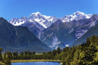 Mountain peaks covered with snow. Mirror glacial Lake Matheson surrounded by mountains Mount Cook