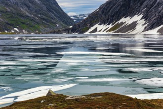 Kingdom of the Snow Queen. Lake Djupvatnet is covered with ice in July. The mountains are covered