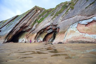 Picturesque cave on the beach. Flysch - underwater rocks exposed at low tide. Low tide in the