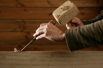 Gouge wood chisel carpenter tool hammer in hand working wooden background