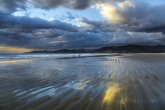 Sunrise over the ocean. Low tide. Strips of sand and water left by the ocean tide. New Zealand,