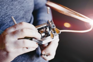 Hands using a mechanical tool with copper wire, emphasizing precision