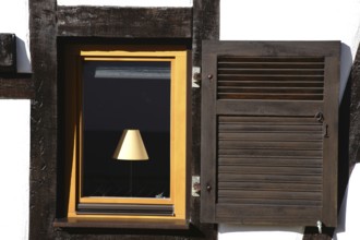 The nostalgic window of a half-timbered house with a lamp behind the window pane
