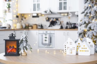 Cozy Christmas decor tiny house of small size on table of festive white modern kitchen. Gift for